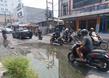 Lubang Jalan Tertutup Genangan,Pengendara Motor di Gajah Mada Waswas