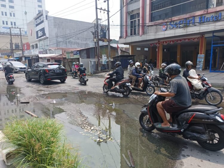 Lubang Jalan Tertutup Genangan,Pengendara Motor di Gajah Mada Waswas
